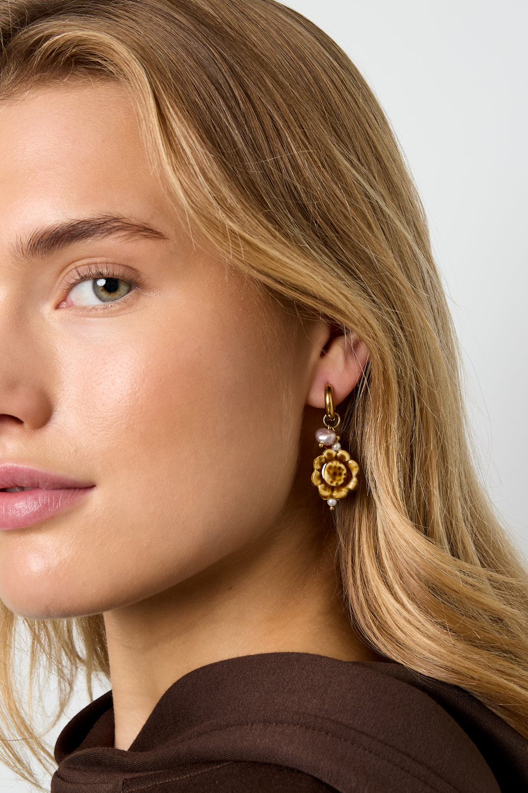Gold flower-shaped Flora earrings worn in the ear with delicate detailing from Sorea Fashion.