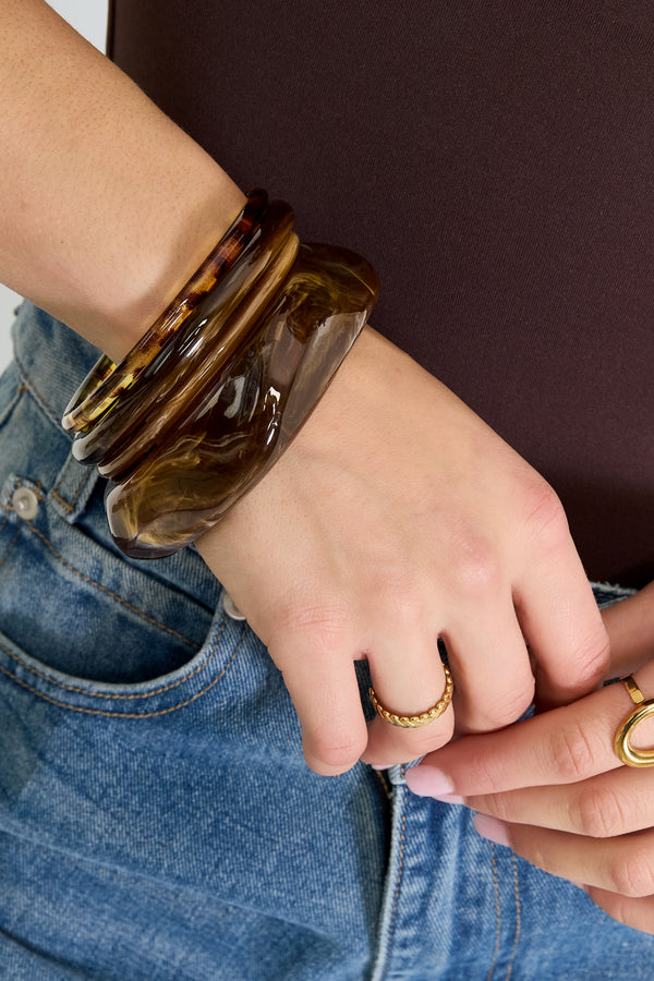 Brown Rubi bangle with a glossy surface worn on the wrist from Sorea Fashion.